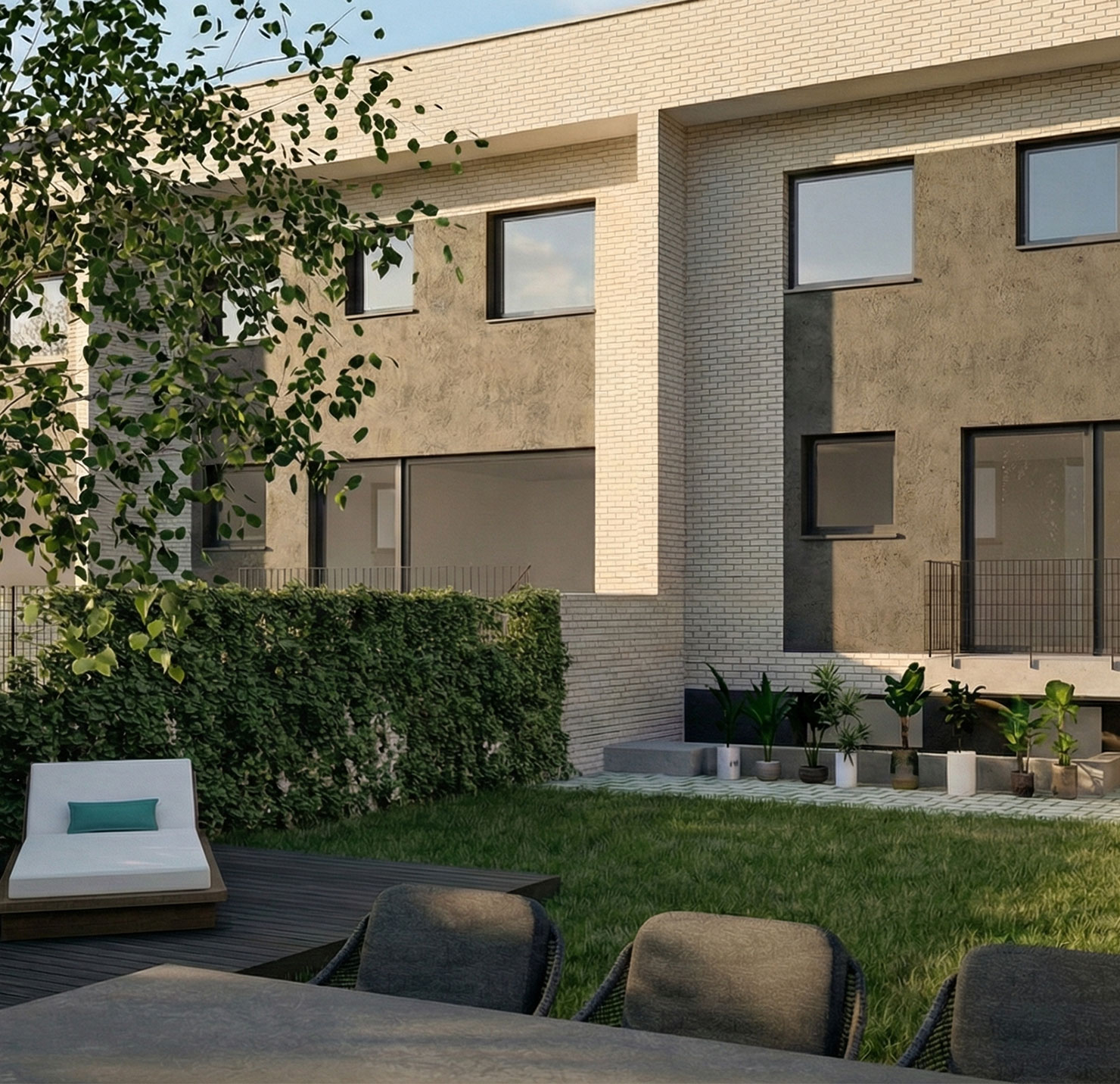 Jardín privado trasero con césped natural y zona de terraza amueblada en chalet de Valdemoro. Muestra espacio para comedor de verano, tumbonas y la fachada posterior moderna con acceso directo al interior.